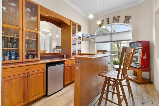 bar with ornamental molding, refrigerator, hanging light fixtures, and light wood finished floors