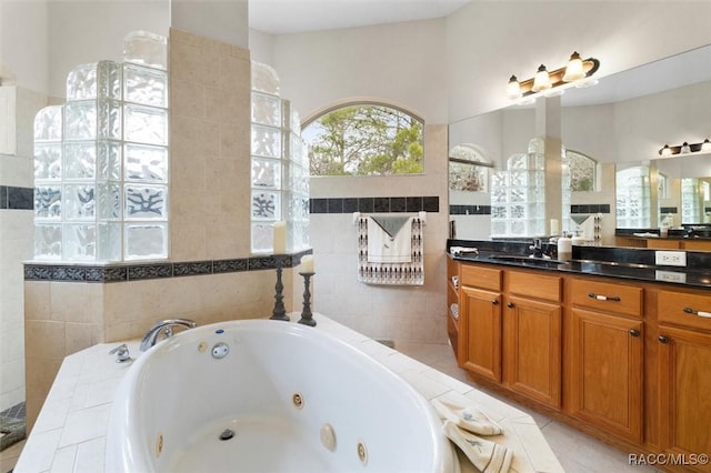 full bathroom featuring a jetted tub, tile walls, and vanity