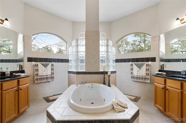 full bath featuring a whirlpool tub, tile patterned floors, tile walls, and vanity