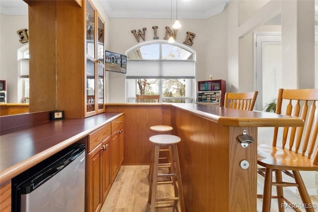 bar with crown molding, pendant lighting, dishwasher, and light wood-style flooring