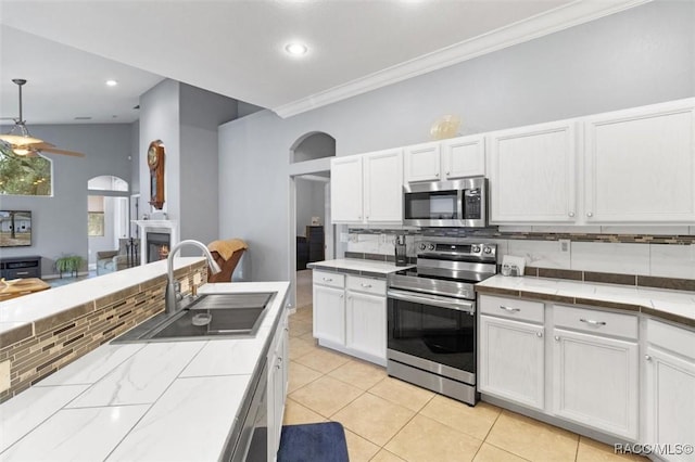 kitchen with tile countertops, appliances with stainless steel finishes, white cabinets, and a sink