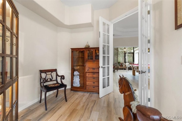 living area with light wood-type flooring, baseboards, and french doors