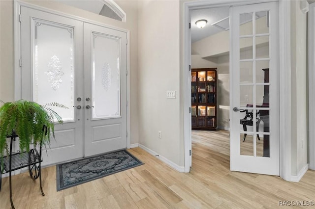 entryway featuring light wood finished floors, french doors, and baseboards