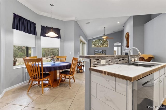 kitchen with light tile patterned floors, white cabinets, dishwasher, decorative light fixtures, and a sink