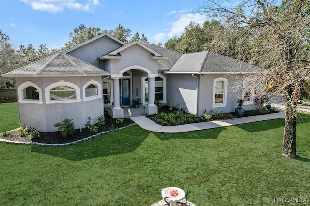 view of front facade featuring a front lawn, roof with shingles, and stucco siding