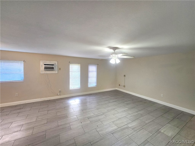 spare room with a textured ceiling, light hardwood / wood-style flooring, a wall mounted AC, and ceiling fan