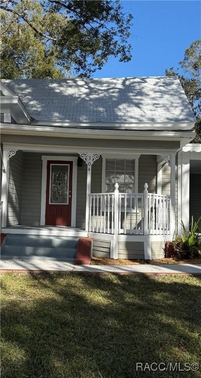 property entrance featuring a porch and a lawn