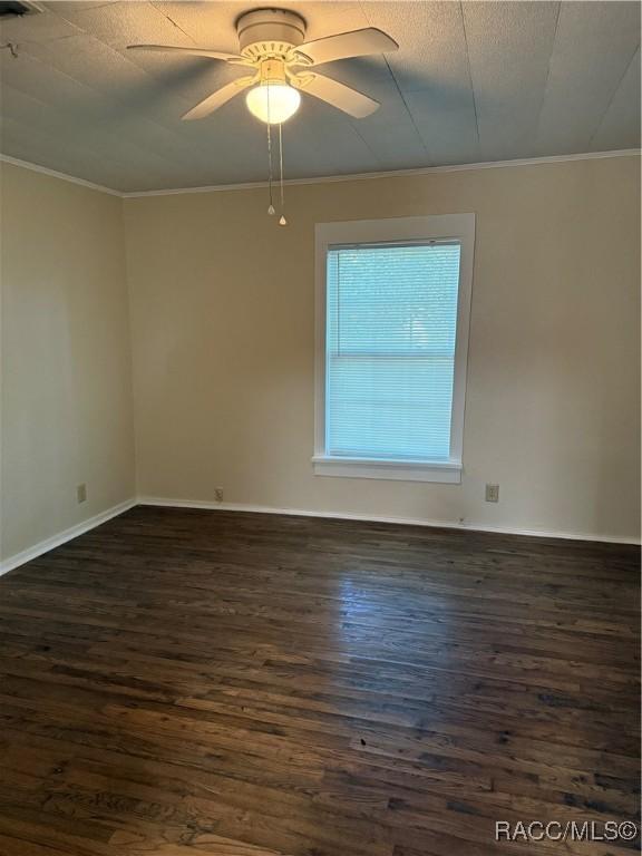 unfurnished room with ceiling fan, crown molding, and dark wood-type flooring