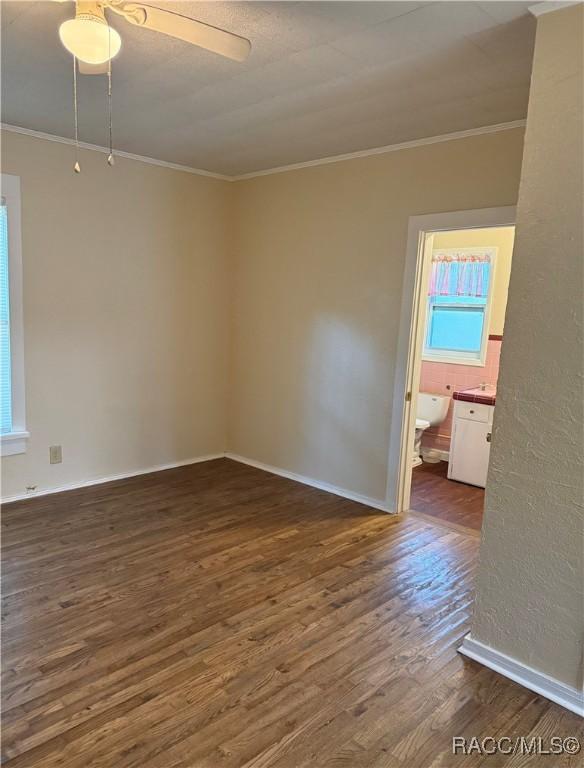 spare room featuring dark hardwood / wood-style flooring, ceiling fan, and crown molding