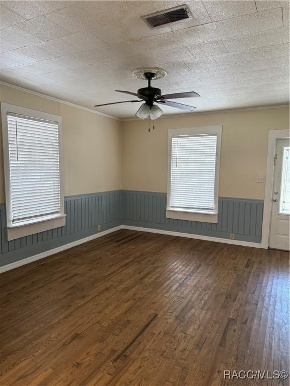 unfurnished room featuring dark hardwood / wood-style flooring, ceiling fan, and ornamental molding