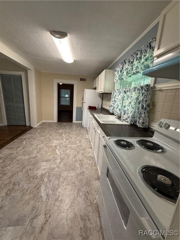 kitchen with a textured ceiling, white appliances, white cabinetry, and sink