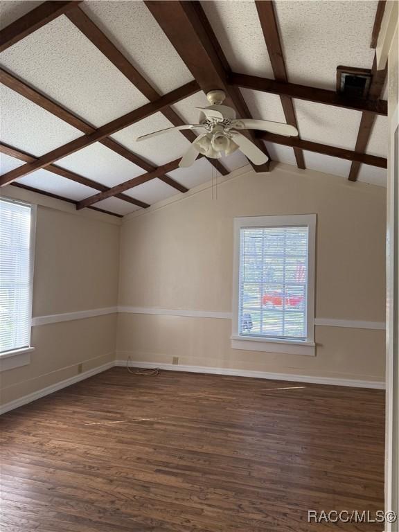 unfurnished room featuring plenty of natural light, ceiling fan, and dark wood-type flooring