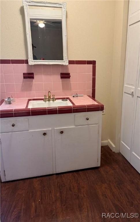 kitchen with white cabinets, tile counters, sink, and dark wood-type flooring