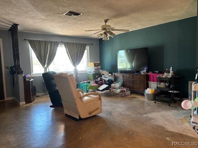 living room with concrete flooring, visible vents, ceiling fan, and a textured ceiling