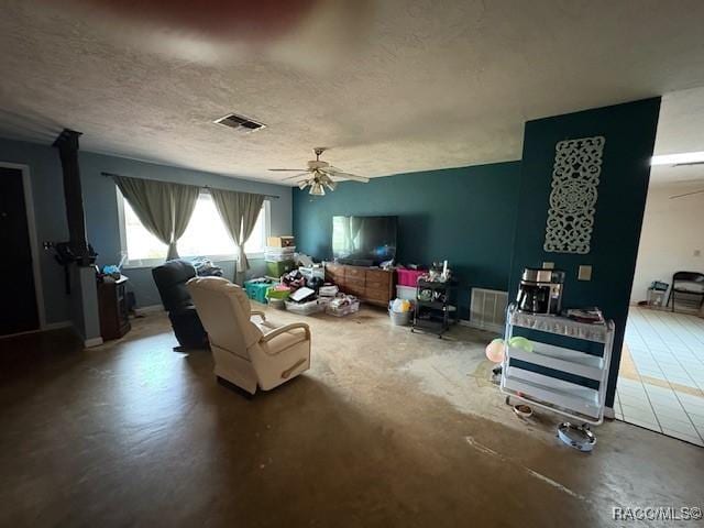 living room with a textured ceiling, visible vents, a ceiling fan, and concrete flooring