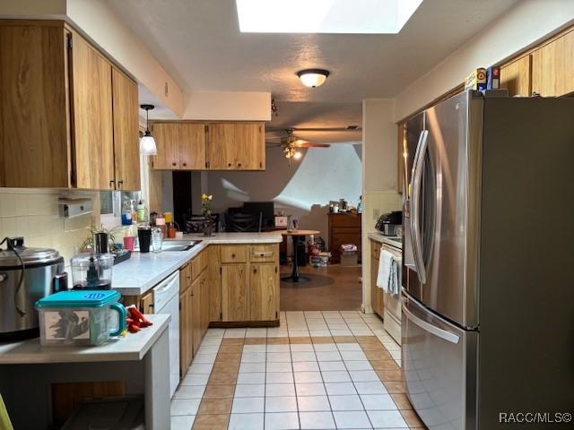 kitchen with light tile patterned floors, freestanding refrigerator, a peninsula, light countertops, and pendant lighting