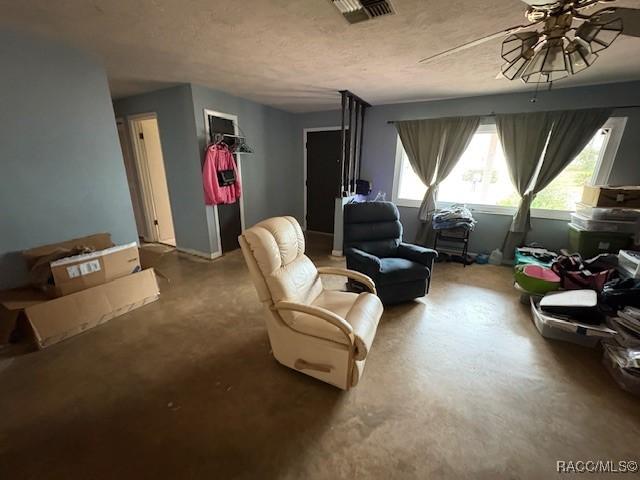 sitting room with visible vents, concrete floors, a textured ceiling, and ceiling fan