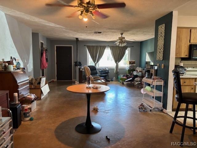 living room featuring finished concrete floors, visible vents, and a ceiling fan