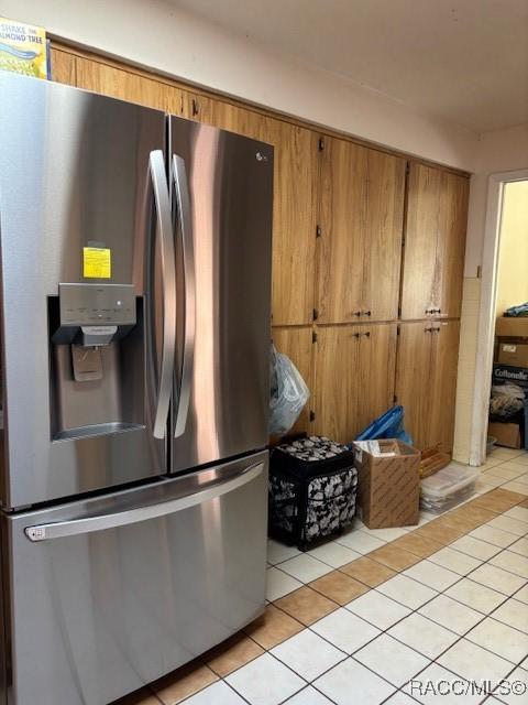 kitchen featuring stainless steel refrigerator with ice dispenser, light tile patterned flooring, and brown cabinets