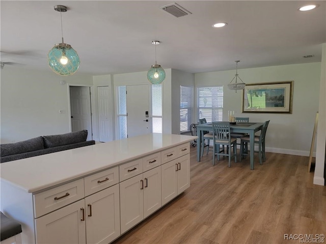 kitchen featuring light hardwood / wood-style flooring, white cabinets, and pendant lighting