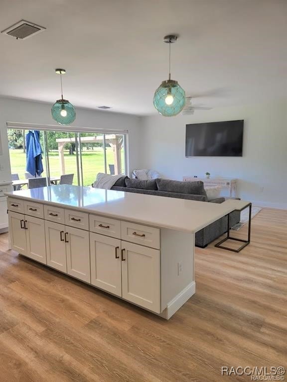 kitchen featuring white cabinets, pendant lighting, light wood-type flooring, and ceiling fan