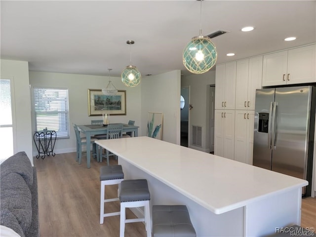 kitchen featuring white cabinets, pendant lighting, stainless steel fridge with ice dispenser, and light hardwood / wood-style flooring