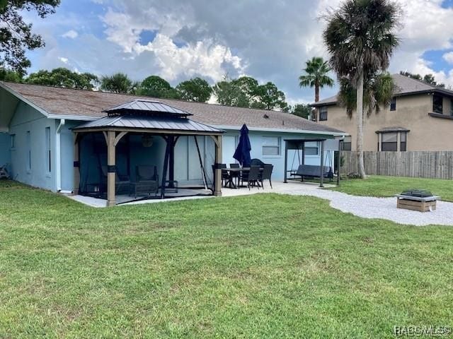 rear view of property featuring a gazebo, a patio, and a lawn