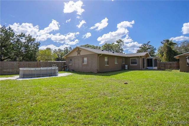 back of property with a lawn and a fenced in pool