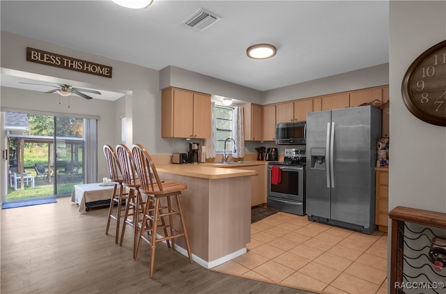 kitchen featuring kitchen peninsula, a kitchen bar, stainless steel appliances, and a wealth of natural light