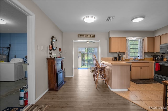 kitchen featuring a healthy amount of sunlight, washer / dryer, light hardwood / wood-style floors, and appliances with stainless steel finishes