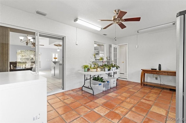 interior space featuring a textured wall, a notable chandelier, light tile patterned floors, and visible vents