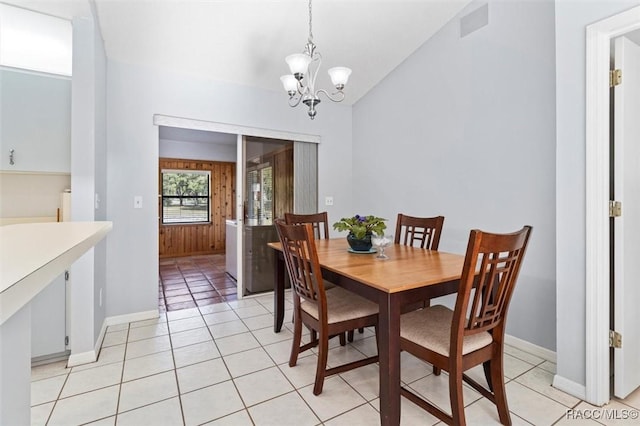 dining area with baseboards, a chandelier, light tile patterned floors, and vaulted ceiling