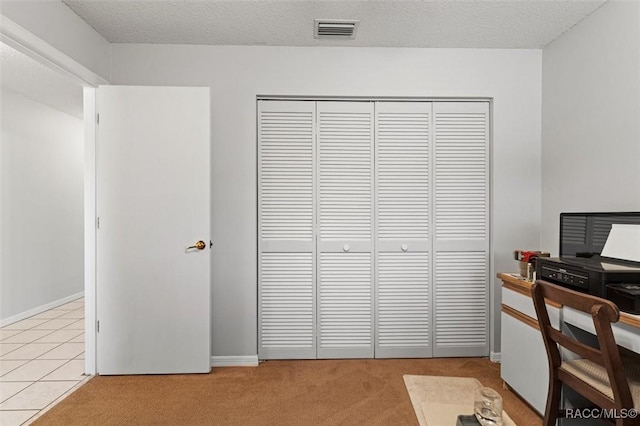 office space with a textured ceiling, visible vents, light carpet, and baseboards