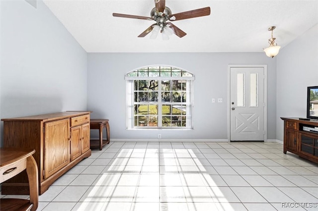 interior space featuring light tile patterned floors, baseboards, ceiling fan, and vaulted ceiling
