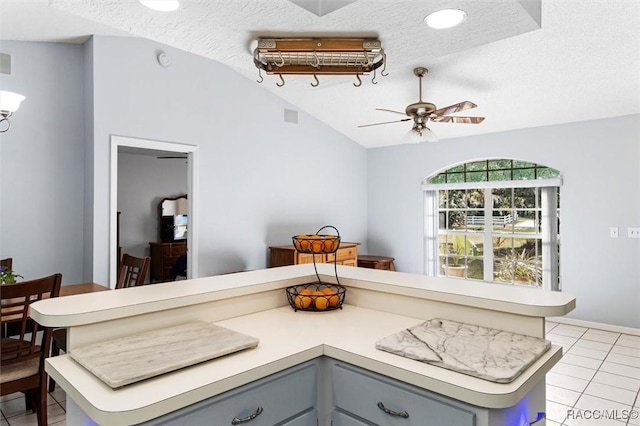 interior space with gray cabinetry, light tile patterned floors, vaulted ceiling, and light countertops