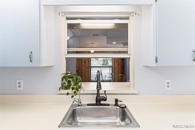 kitchen with a sink, light countertops, and white cabinets