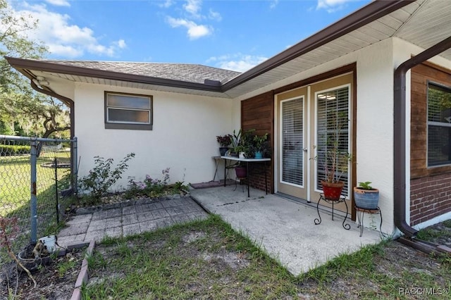 back of house with french doors, a patio area, fence, a shingled roof, and stucco siding