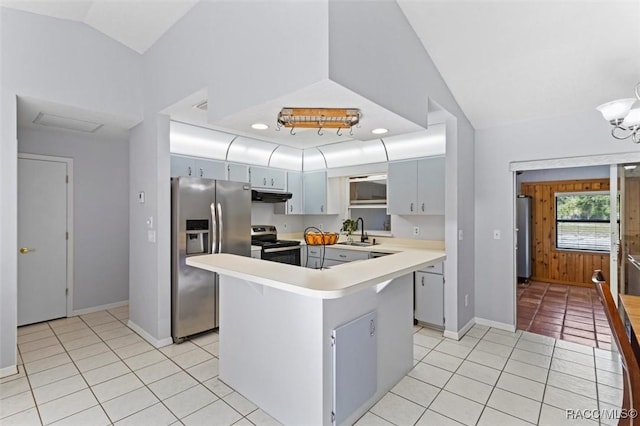 kitchen featuring light tile patterned flooring, appliances with stainless steel finishes, a sink, lofted ceiling, and under cabinet range hood