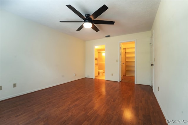 unfurnished bedroom with dark hardwood / wood-style flooring, connected bathroom, a spacious closet, and ceiling fan