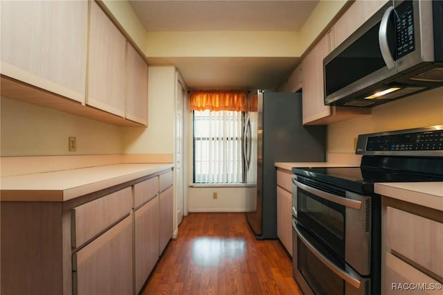 kitchen with stainless steel appliances, light brown cabinets, and dark hardwood / wood-style flooring