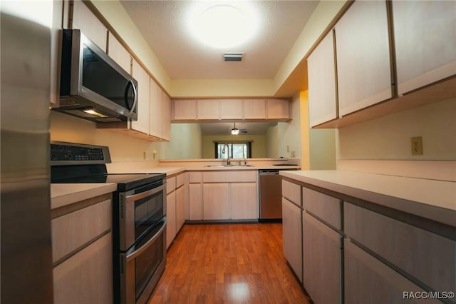 kitchen with sink, light hardwood / wood-style flooring, stainless steel appliances, and kitchen peninsula