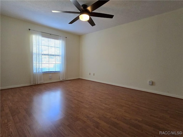 unfurnished room featuring dark wood-type flooring and ceiling fan