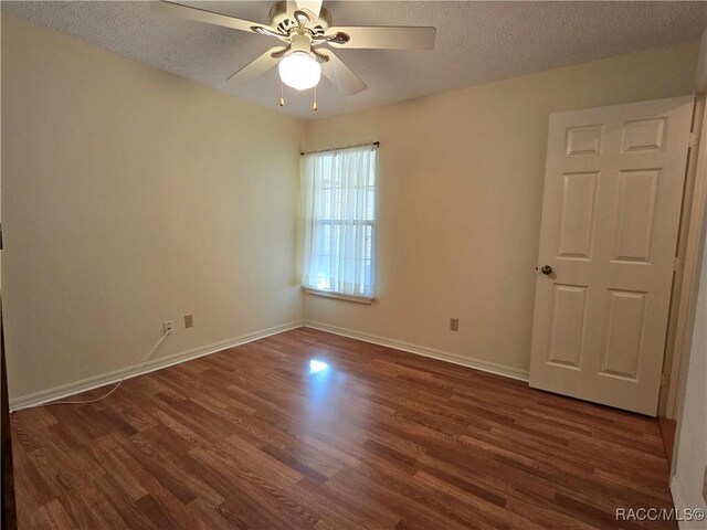 empty room with ceiling fan, dark wood-type flooring, and a textured ceiling