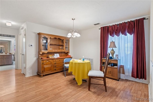 dining area featuring light hardwood / wood-style flooring and a notable chandelier