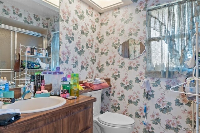 bathroom featuring vanity, toilet, and walk in shower