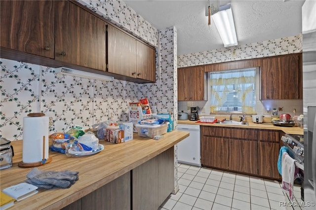 kitchen with light tile patterned flooring, white dishwasher, sink, a textured ceiling, and electric range oven