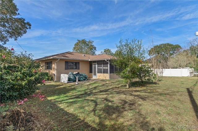 back of house with a sunroom and a lawn