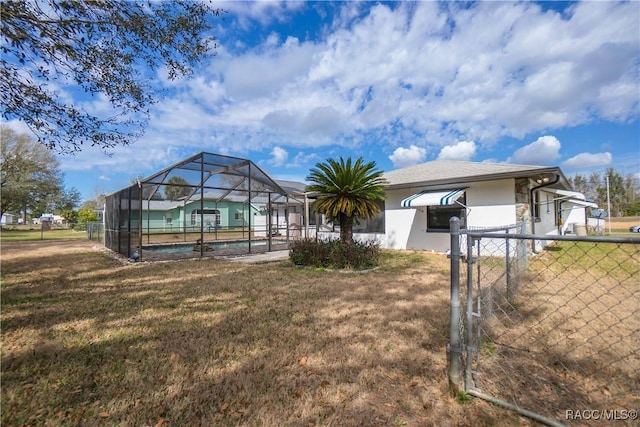 rear view of property with a lanai and a lawn