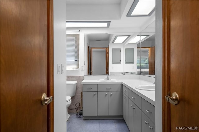 bathroom featuring toilet, tile walls, and vanity