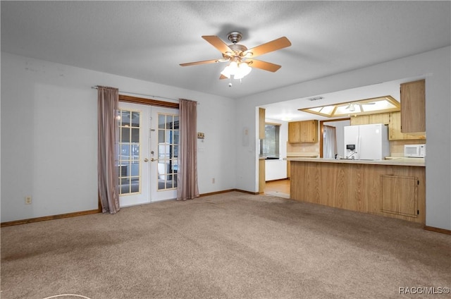 unfurnished living room with french doors, light colored carpet, and ceiling fan